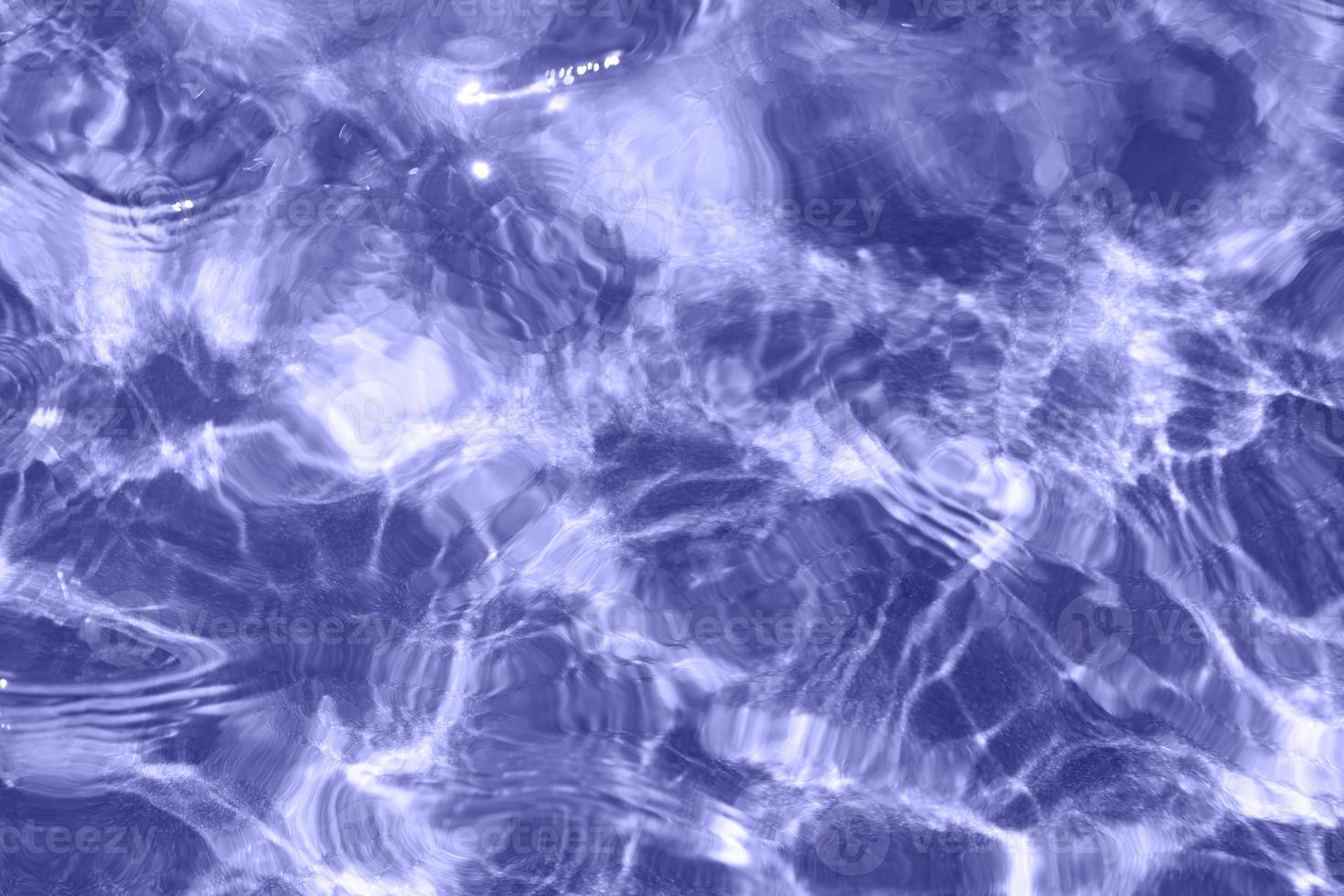Very peri rippled water surface of swimming pool. Background of water repainted in trendy very peri color of the year 2022. Summer holidays, vacations resort concept. photo