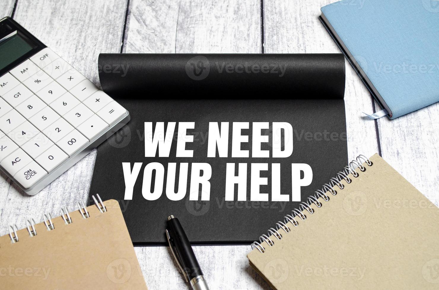 In the notebook the text we NEED YOUR HELP, with calculator and pen photo
