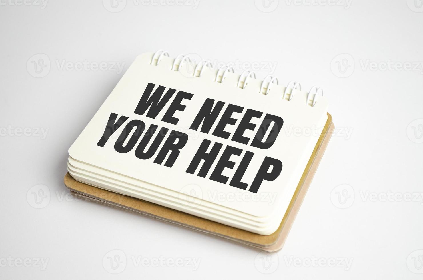 Words We need your Help text on notepad and pen photo