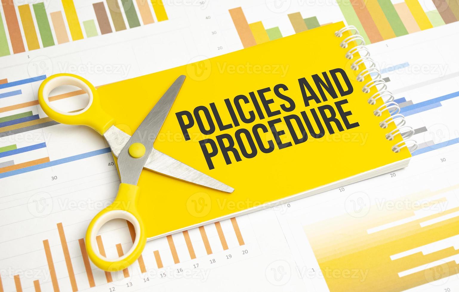 policies and procedure word written on yellow notebook and charts photo