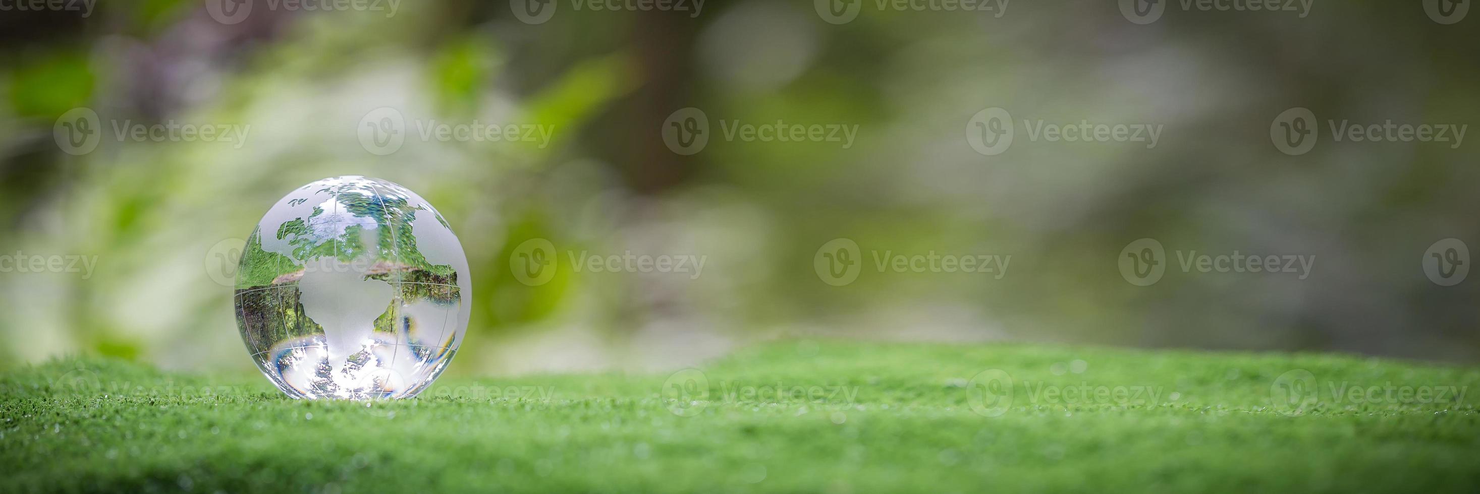 Globe planet glass in green forest with bokeh nature lights. world environment day. concept of environment conservation, protect ecology earth and environmental eco-friendly life banner and copy space photo