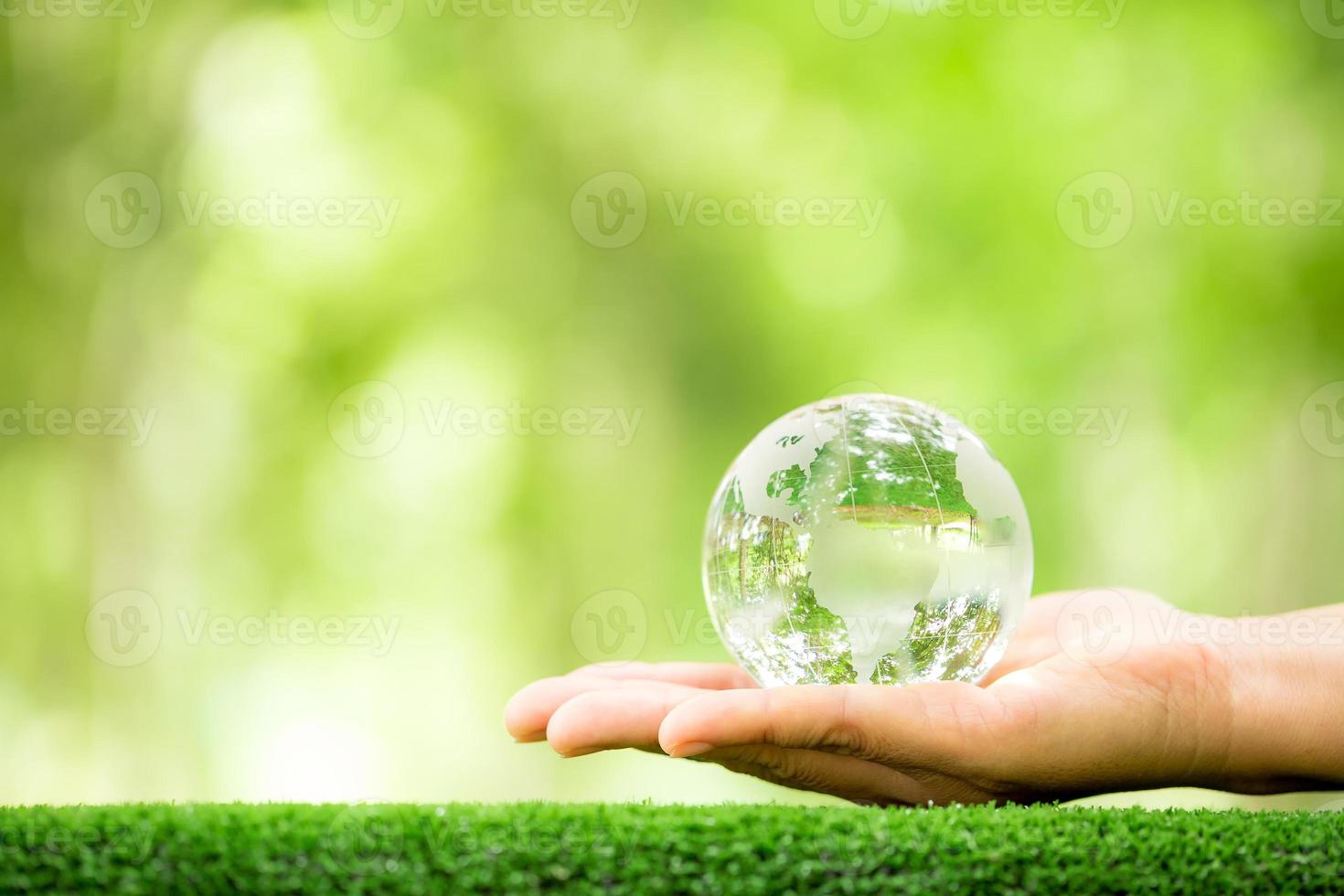 Human hand holding globe planet glass In green forest with bokeh nature lights. world environment day. concept for environment conservation, protect ecology earth and environmental eco-friendly life. photo