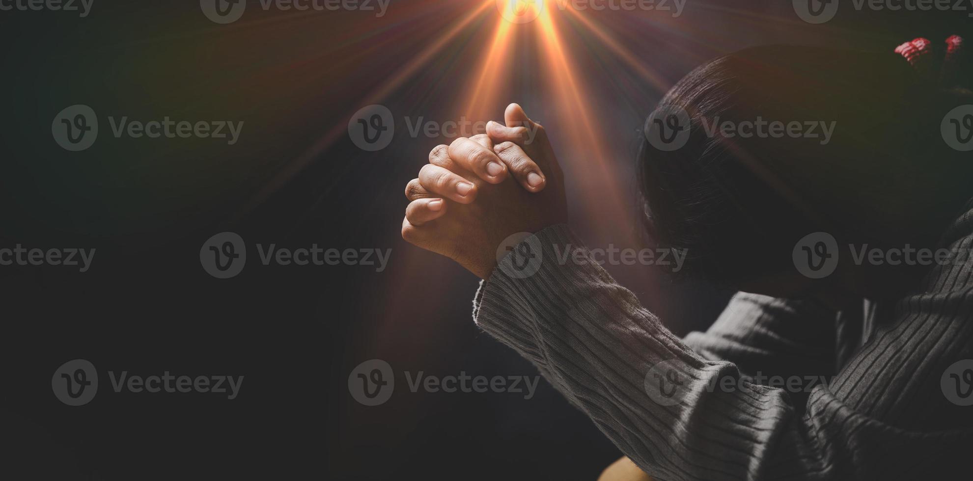 Christ religion and christianity worship or pray concept. Christian catholic woman are praying to god in dark at church. Prayer person hand in black background. Girl believe and faith in jesus christ. photo