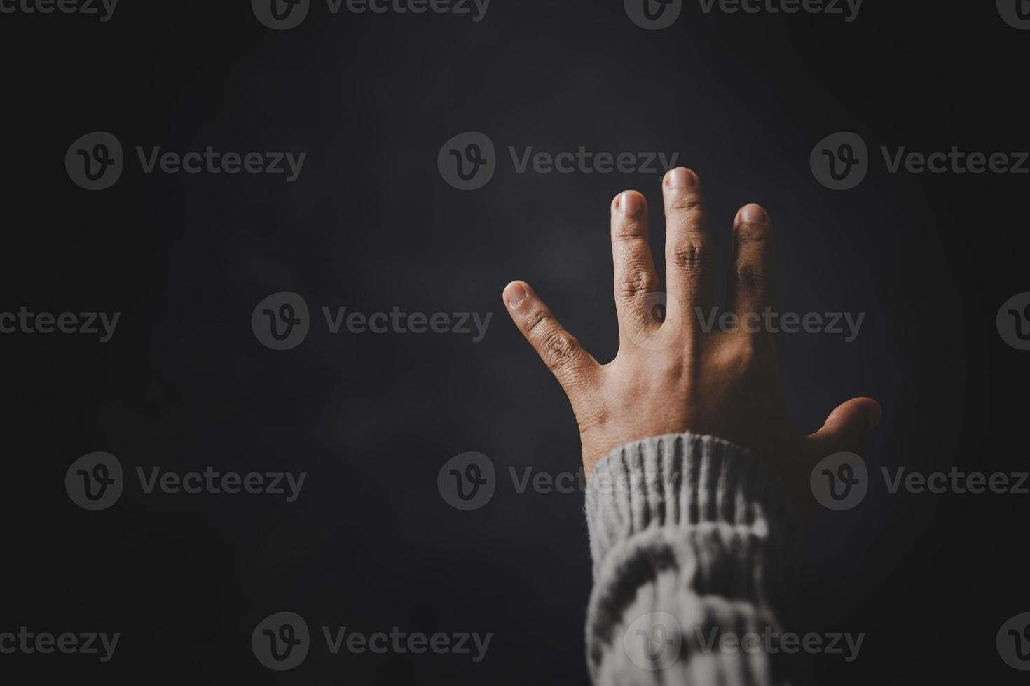 mano de persona de oración en fondo negro. la mujer católica cristiana está rezando a dios en la oscuridad en la iglesia. chica cree y fe en jesucristo. la religión de cristo y el cristianismo adoran o rezan concepto. foto