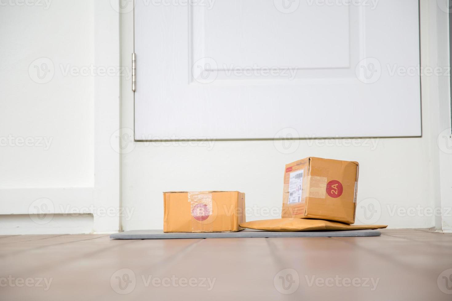 Cardboard parcel box near door on floor. Online shopping, boxes delivered to your front door. Easy to steal when nobody is home. Parcel in cardboard box on doorstep. Delivery service photo