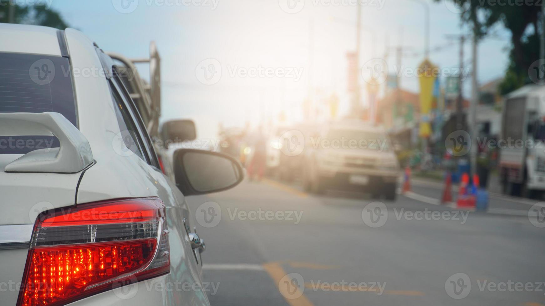 Rear side of white car driving or stop beside on the asphalt road. wtih other cars to beside. blurred of buildings in the city of Thailand. photo