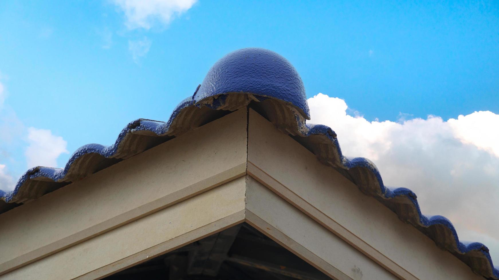 Corner of the roof of Hip Roof tiles arranged on roof structure. On the Primary fascia and Fascia build-out . Under the blue sky and white clouds. photo