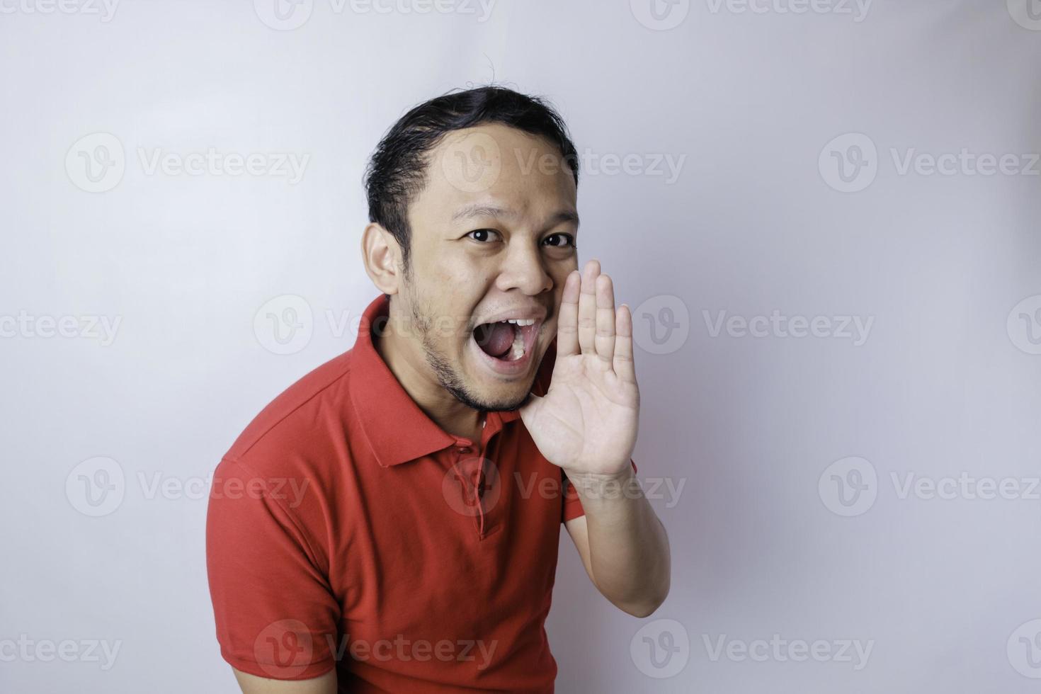 Young attractive man wearing a red t-shirt shouting and screaming loud with a hand on his mouth. communication concept. photo