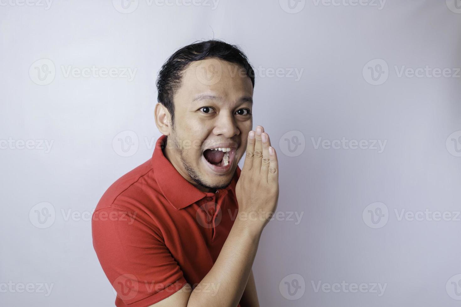 Young attractive man wearing a red t-shirt shouting and screaming loud with a hand on his mouth. communication concept. photo