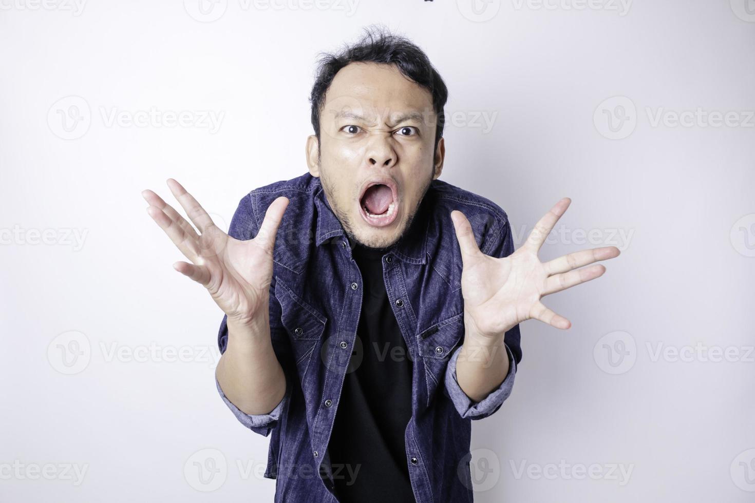 A dissatisfied young Asian man looks disgruntled wearing blue navy shirt irritated face expressions photo