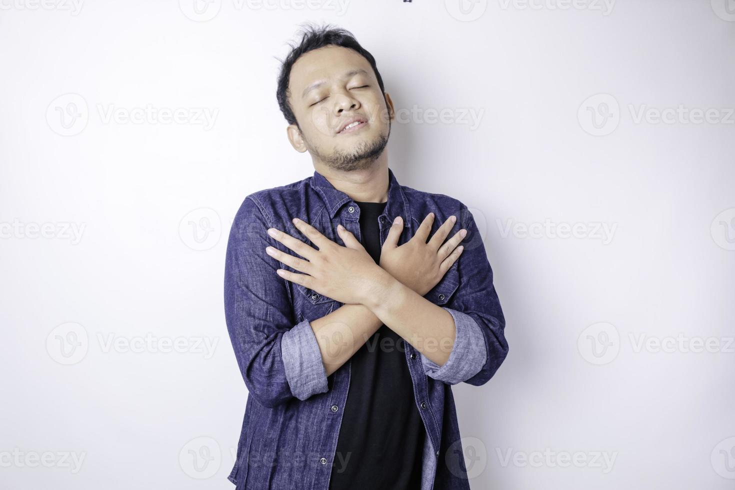 Young beautiful Asian man wearing casual navy blue shirt over white background hugging himself happy and positive, smiling confident. Self love and self care photo