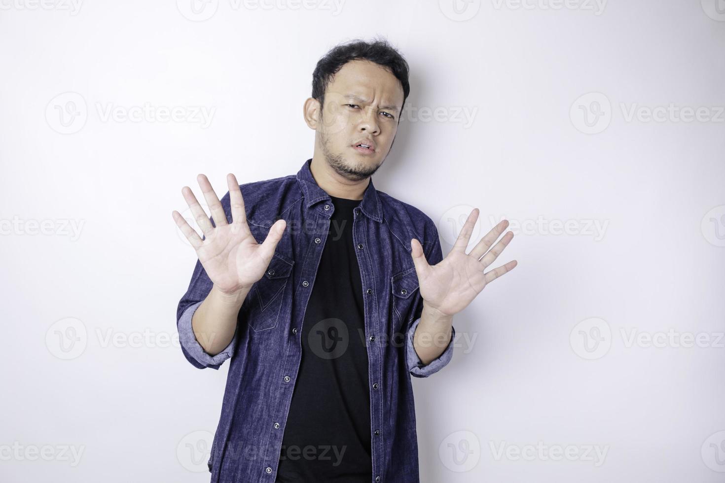 Young Asian man isolated on white background face covered by fingers frightened and nervous. photo