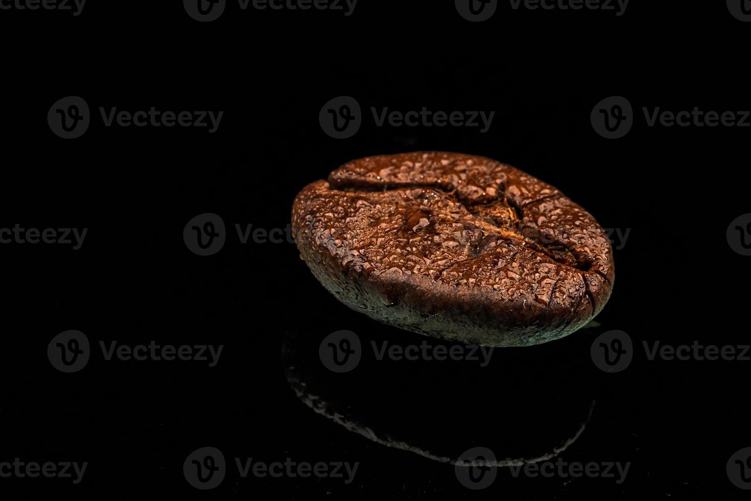 una sola toma macro de grano de café con gotas de agua y reflejo. fondo negro foto