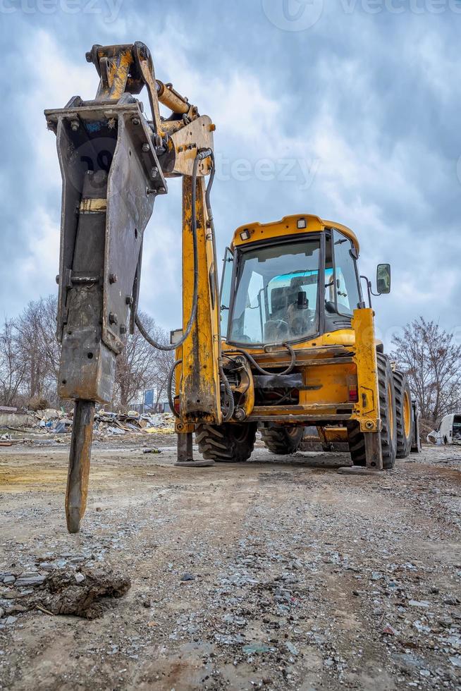 Excavator with hydraulic breaker hammer for the destruction of concrete and hard rock at the construction site or quarry. Demolition equipment photo