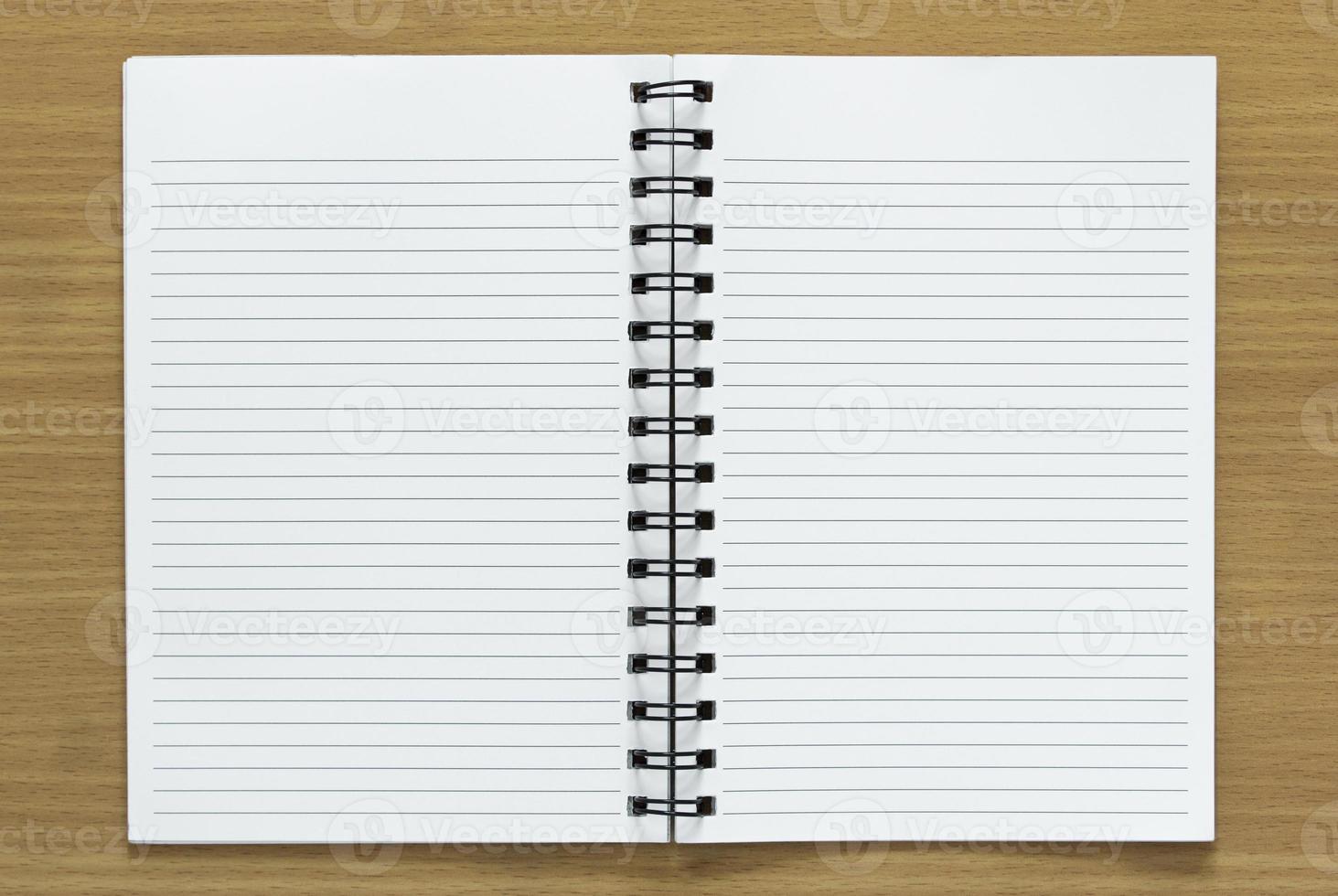 open spiral notebook on wood background photo
