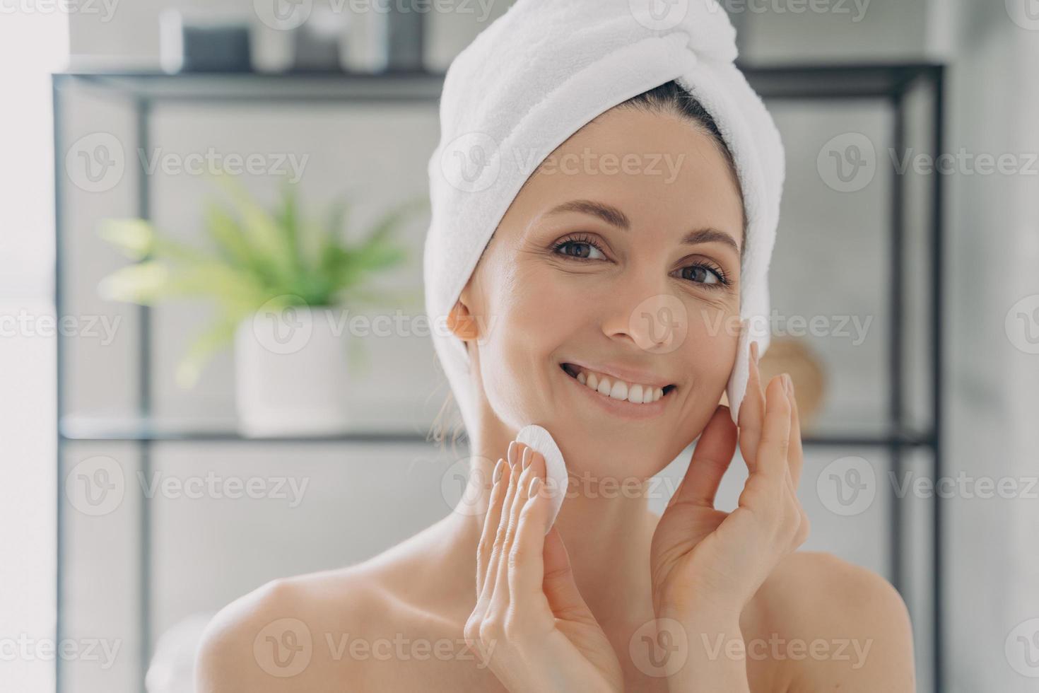 mujer hispana limpiando la piel facial con toallitas de algodón después de la ducha quitando el maquillaje. rutina de cuidado de la piel foto