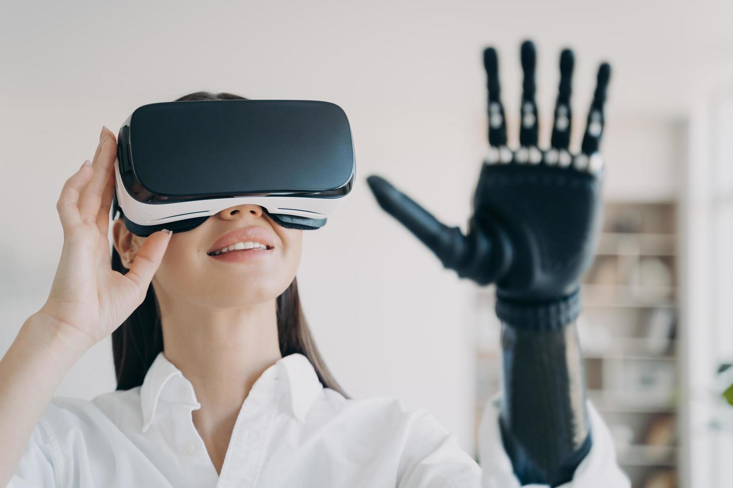 Woman with bionic prosthetic arm testing virtual reality glasses, experiencing augmented cyberspace photo