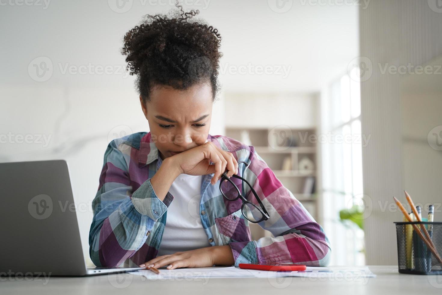 Focused stressed mixed race school student girl studying preparing for exam doing homework at home photo