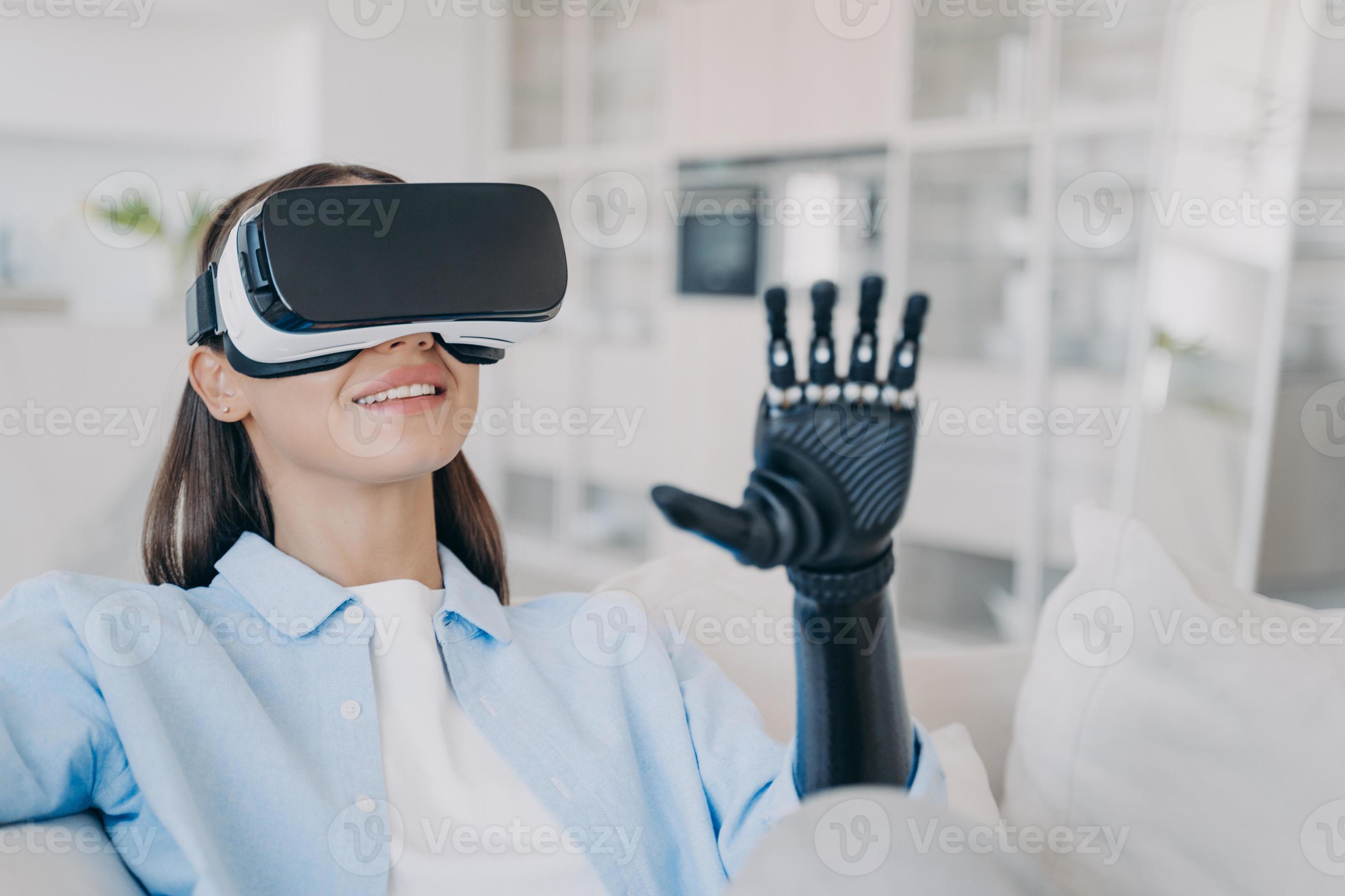 Girl in VR glasses interacts with virtual reality by prosthetic arm. Rehabilitation disabled