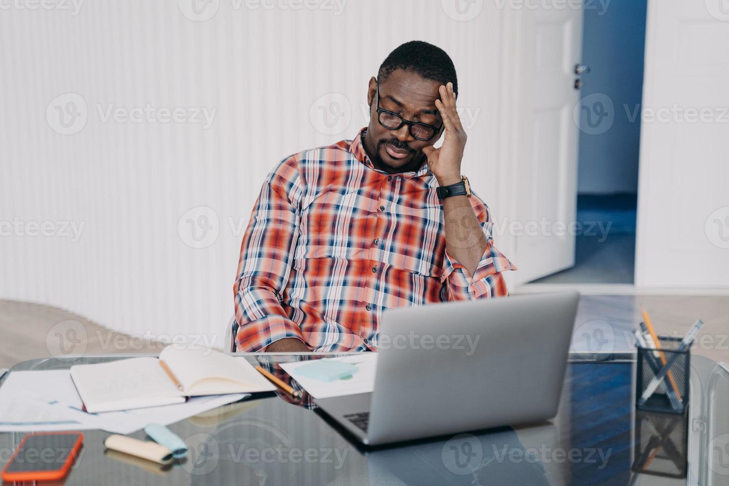 Upset tired african american man sitting at laptop solving working problems. Difficulties in job photo