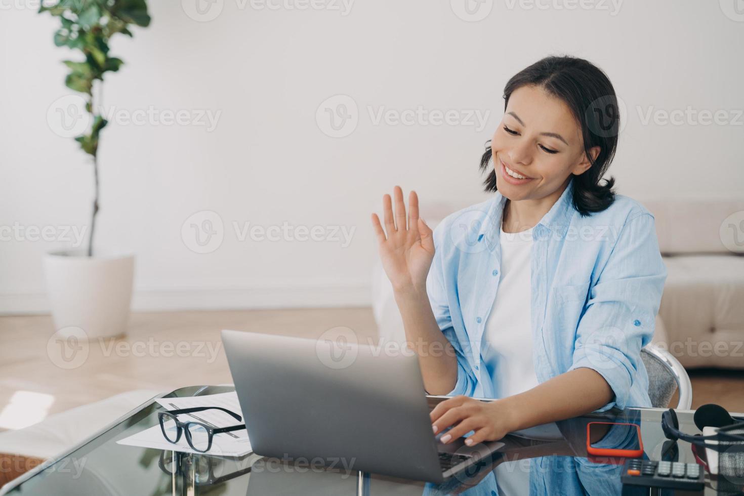 la mujer de negocios trabaja en la computadora portátil, saluda, tiene una videollamada con el cliente en la oficina. trabajo remoto foto