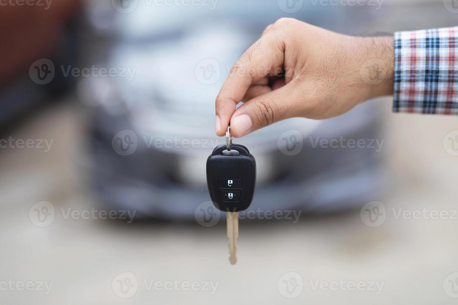 el vendedor entrega las llaves del auto nuevo a los clientes en la sala de exposición. foto