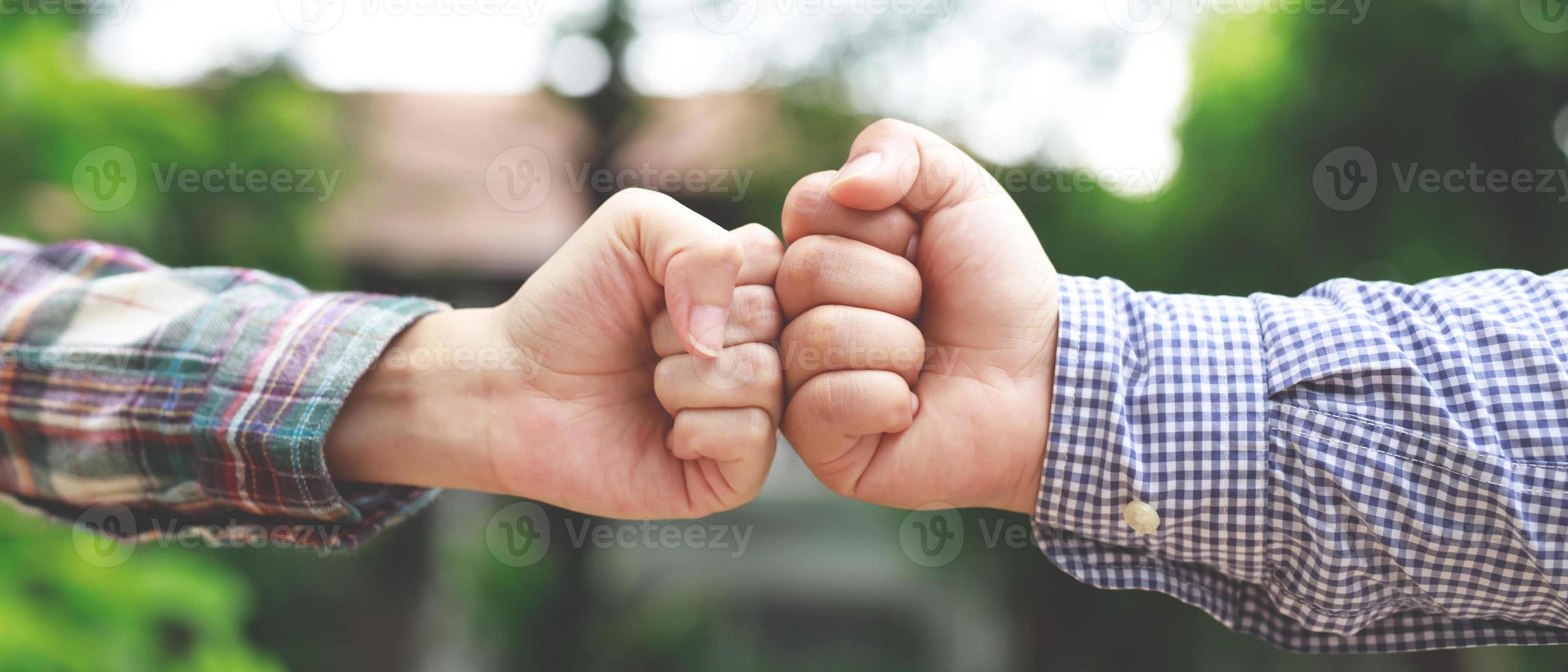 Hands of  two business people wear making a fist pump together after good deal. success and show strength power of teamwork concept. photo