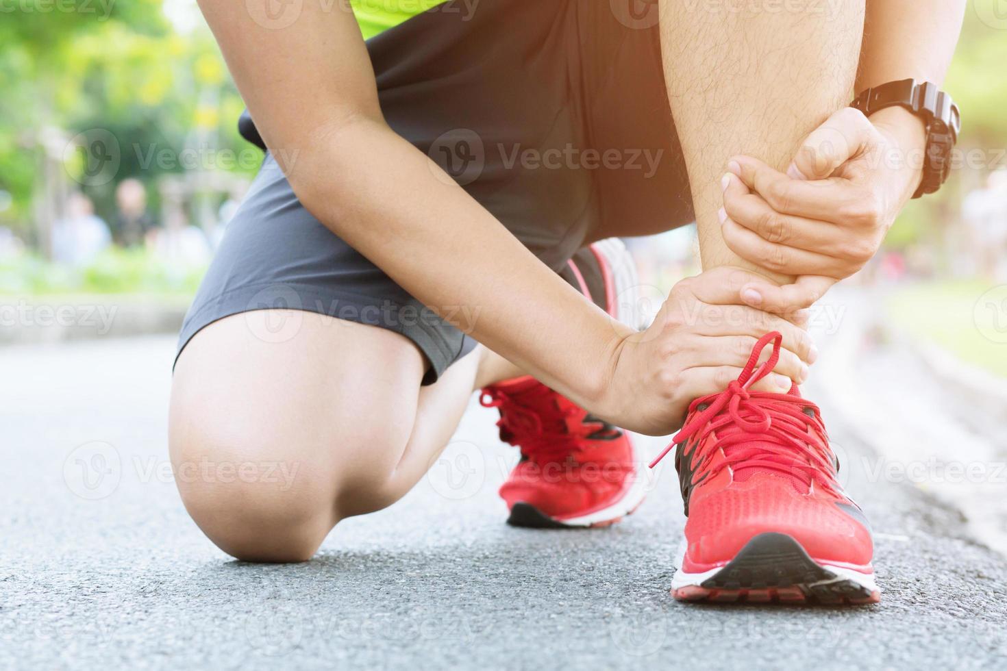 Runner touching painful twisted or broken ankle. Athlete runner training accident. Sport running ankle sprained sprain cause injury knee. and pain with leg bones.  Focus red legs on to show pain. photo