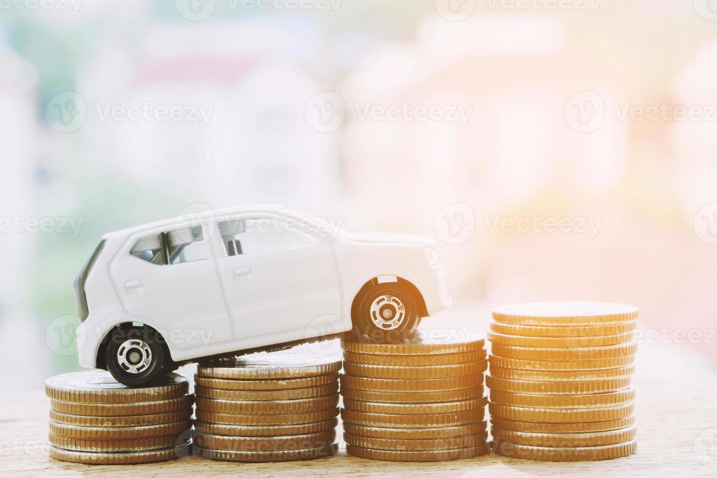 cierre la pila de monedas y coches de juguete en la mesa, ahorre y administre dinero para el éxito del negocio de transporte foto