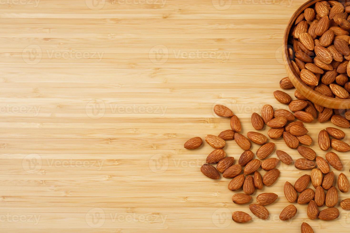 Almonds in brown wooden bowl on old wooden table background photo