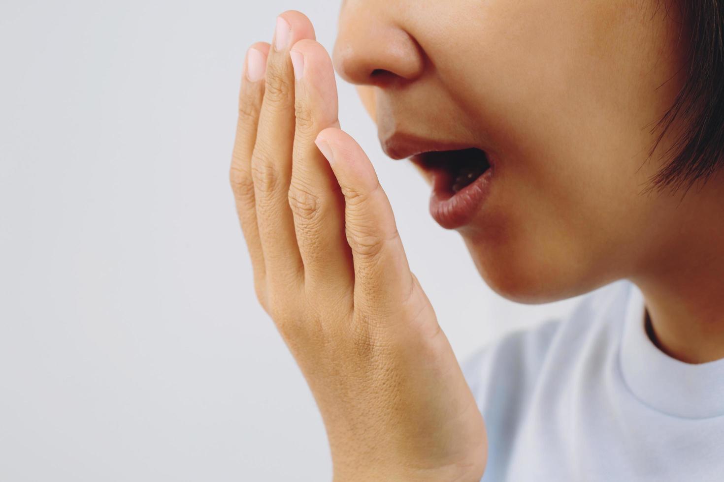 mujer asiática comprobando su aliento con la prueba de la mano. concepto de atención médica. foto