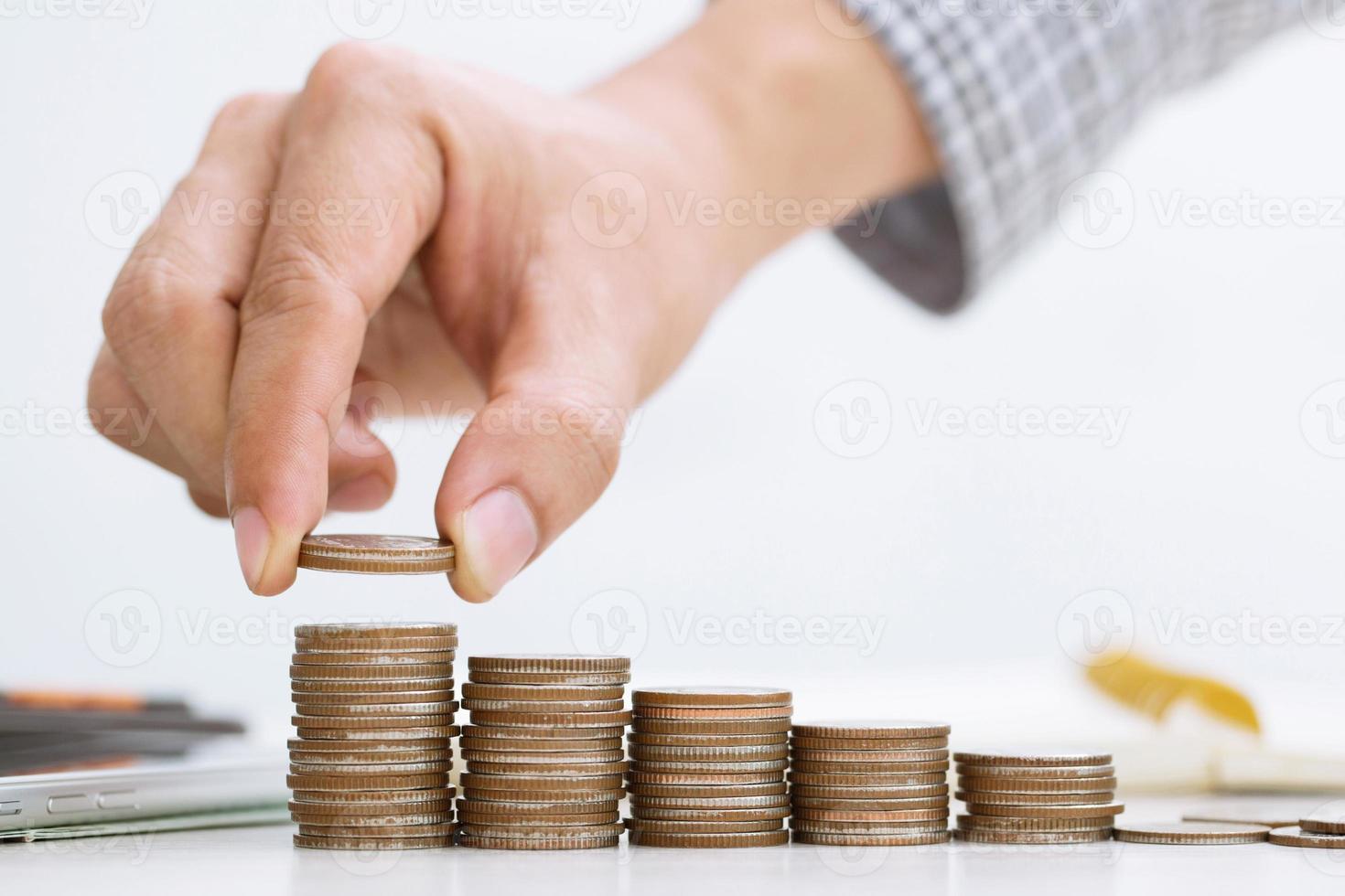 close up hand business man accounting calculator with savings money coins stacked row with hand putting coins in jug glass. concept Write Finance accounting. photo