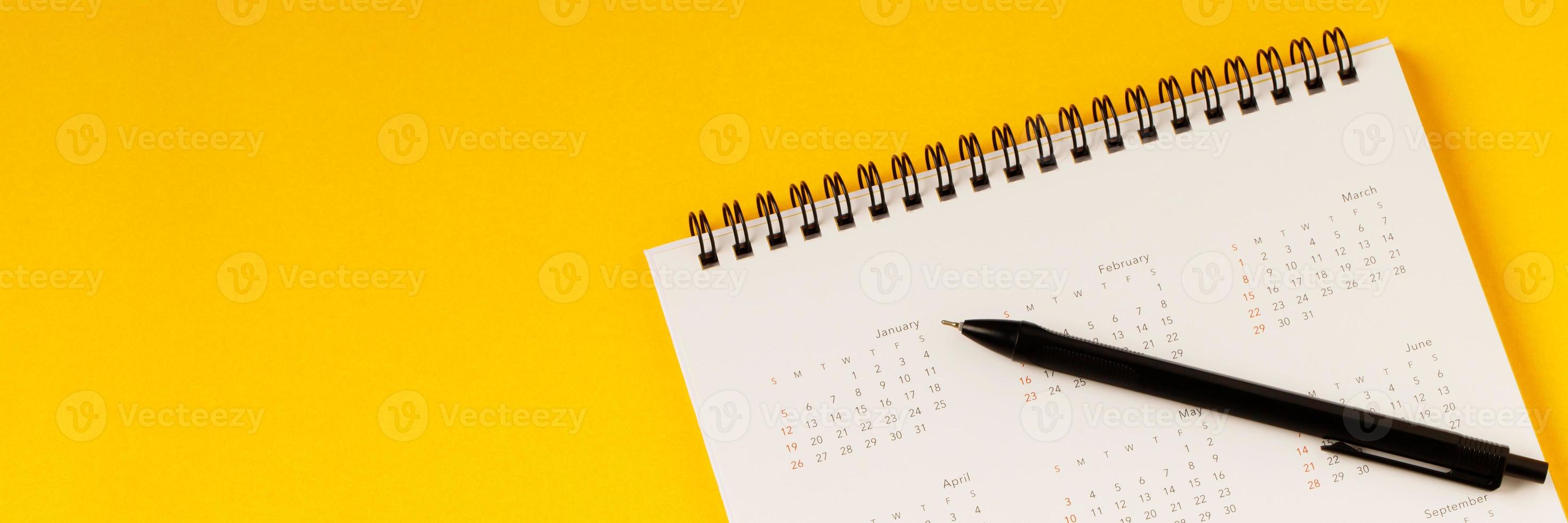 close up top view calendar schedule to make appointment meeting or manage timetable each day lay on yellow background for planning work and travel concept. photo