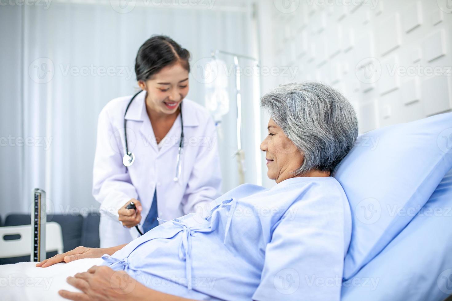 Beautiful asian doctor with stethoscope and document folder, examine the symptom for patient in the recovery room. Healthcare and medicine concept. photo