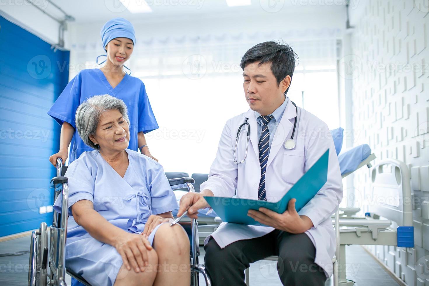 asian doctor with stethoscope and document folder, examine the symptom for senior patient in the recovery room. Healthcare and medicine concept. photo