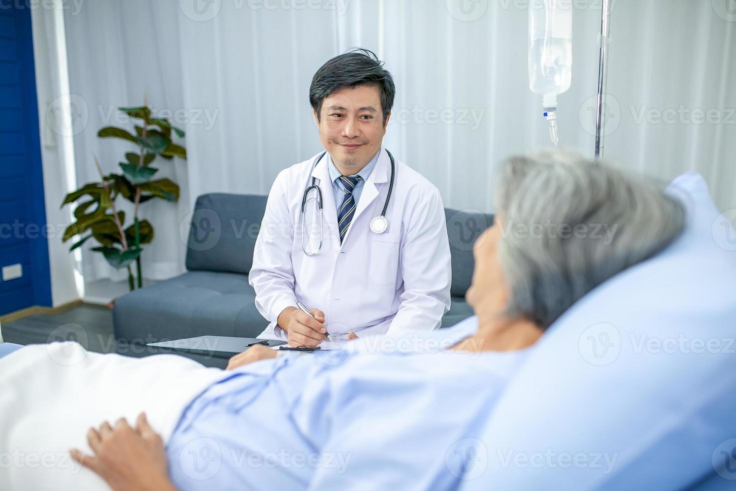 asian doctor with stethoscope and document folder, examine the symptom for patient in the recovery room. Healthcare and medicine concept. photo