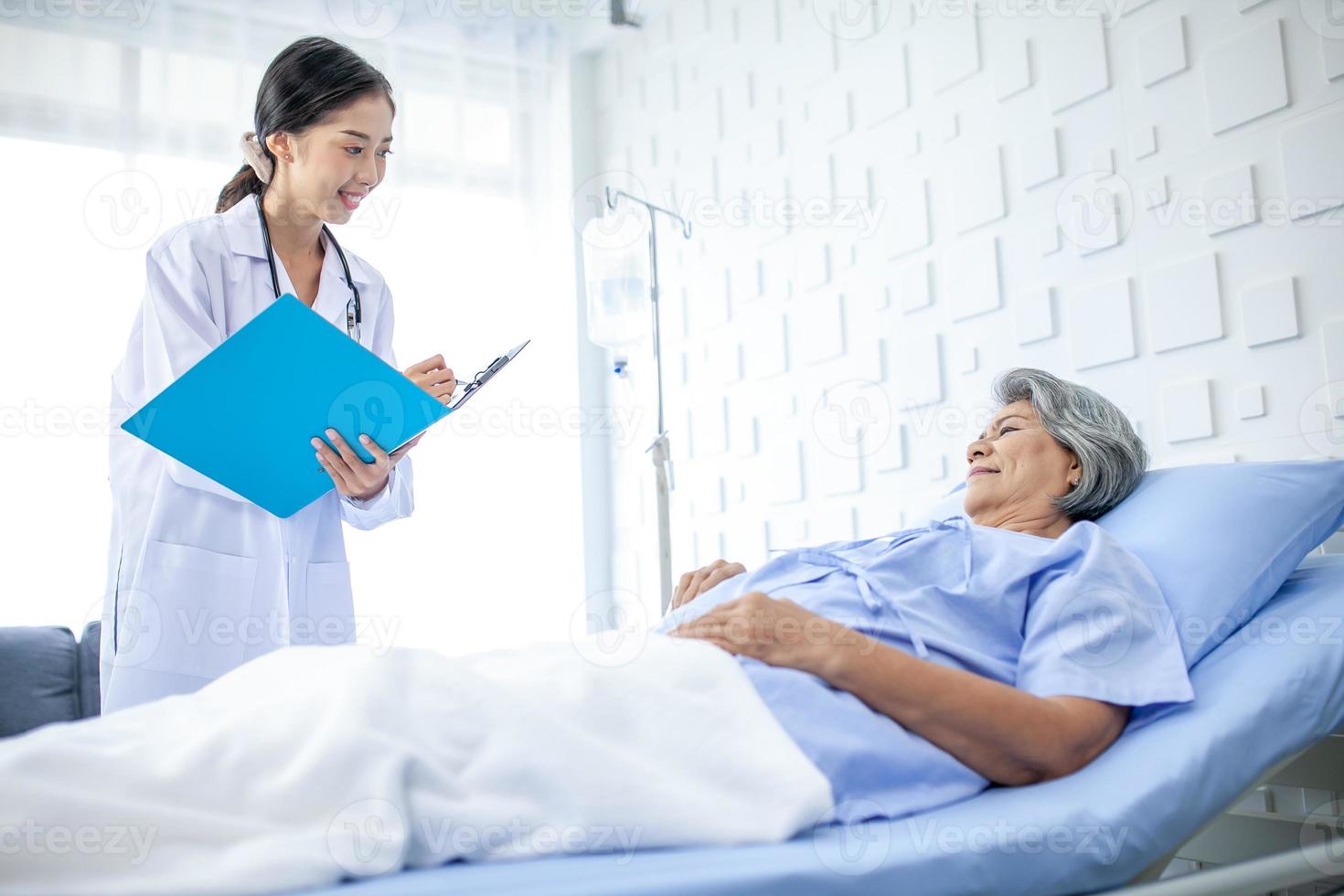 Beautiful asian doctor with stethoscope and document folder, examine the symptom for patient in the recovery room. Healthcare and medicine concept. photo