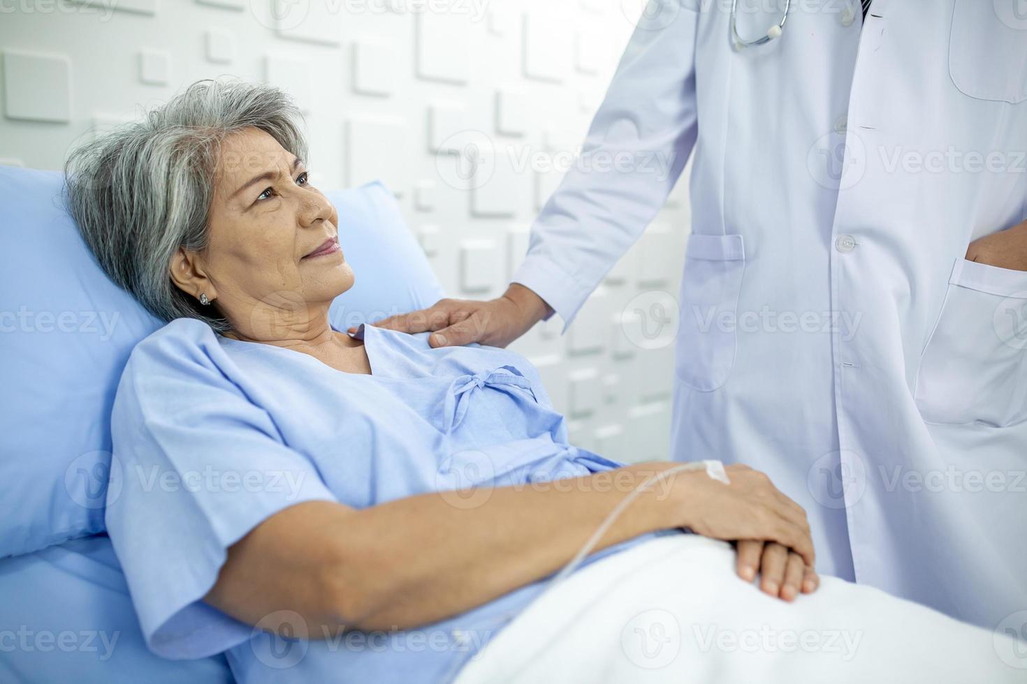 médico asiático apoyando y animando a un paciente mayor en el hospital, hablando sonriendo con comodidad. concepto de salud y medicina. foto