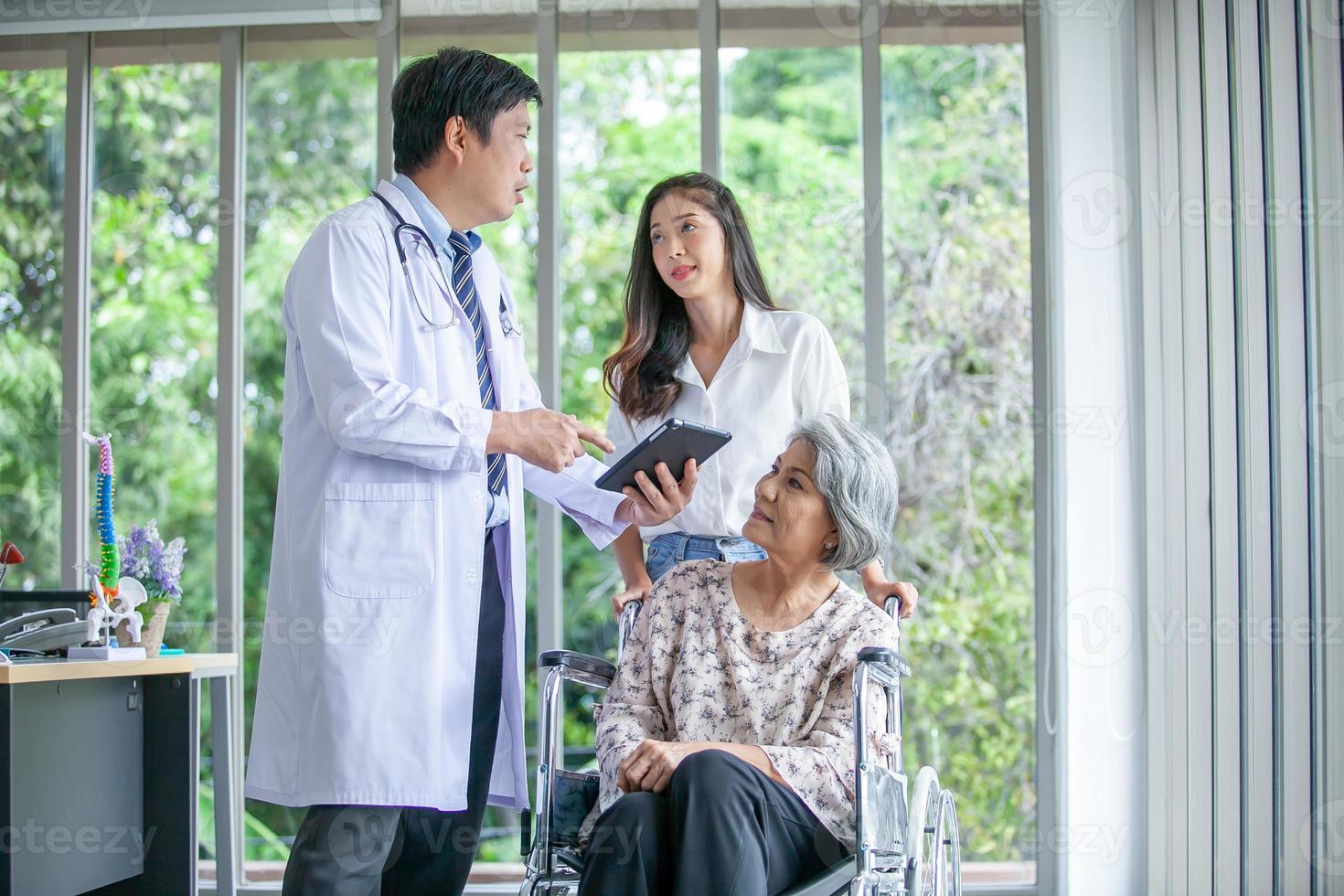 médico asiático explicando la enfermedad a un paciente mayor con una tableta sonriendo cómodamente en el hogar, el concepto de atención médica y medicina. foto