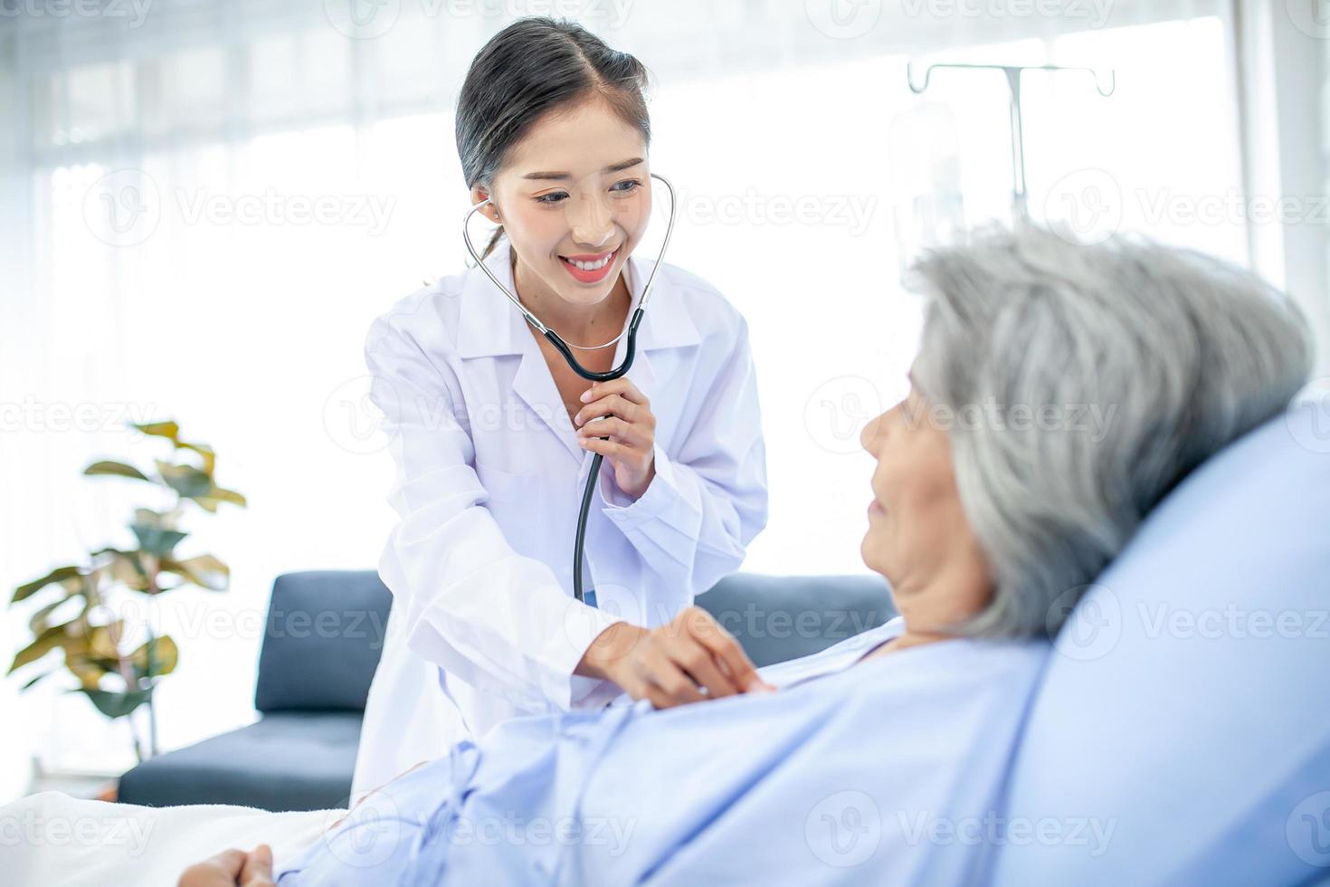 Beautiful asian doctor with stethoscope and document folder, examine the symptom for patient in the recovery room. Healthcare and medicine concept. photo