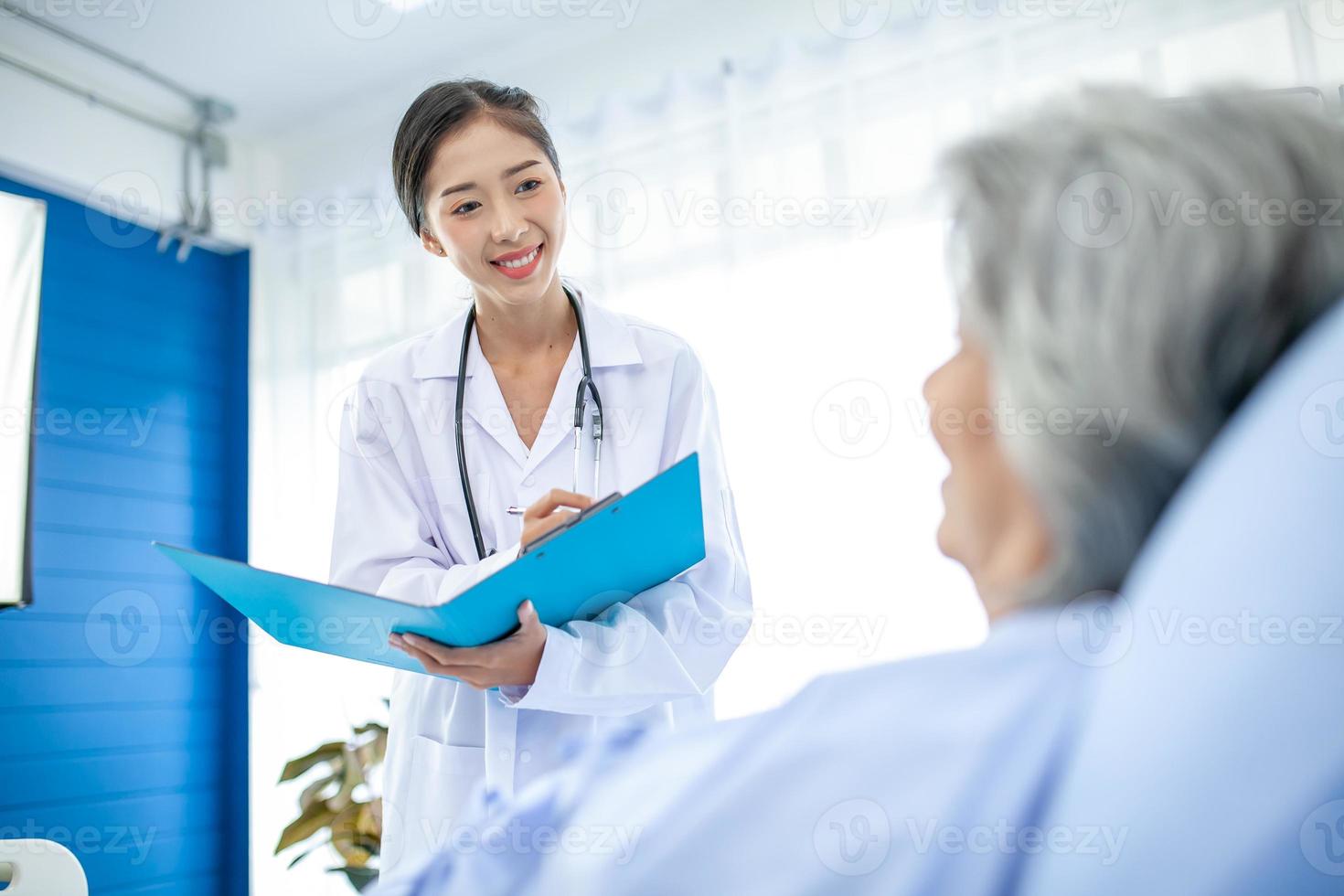 Beautiful asian doctor with stethoscope and document folder, examine the symptom for patient in the recovery room. Healthcare and medicine concept. photo