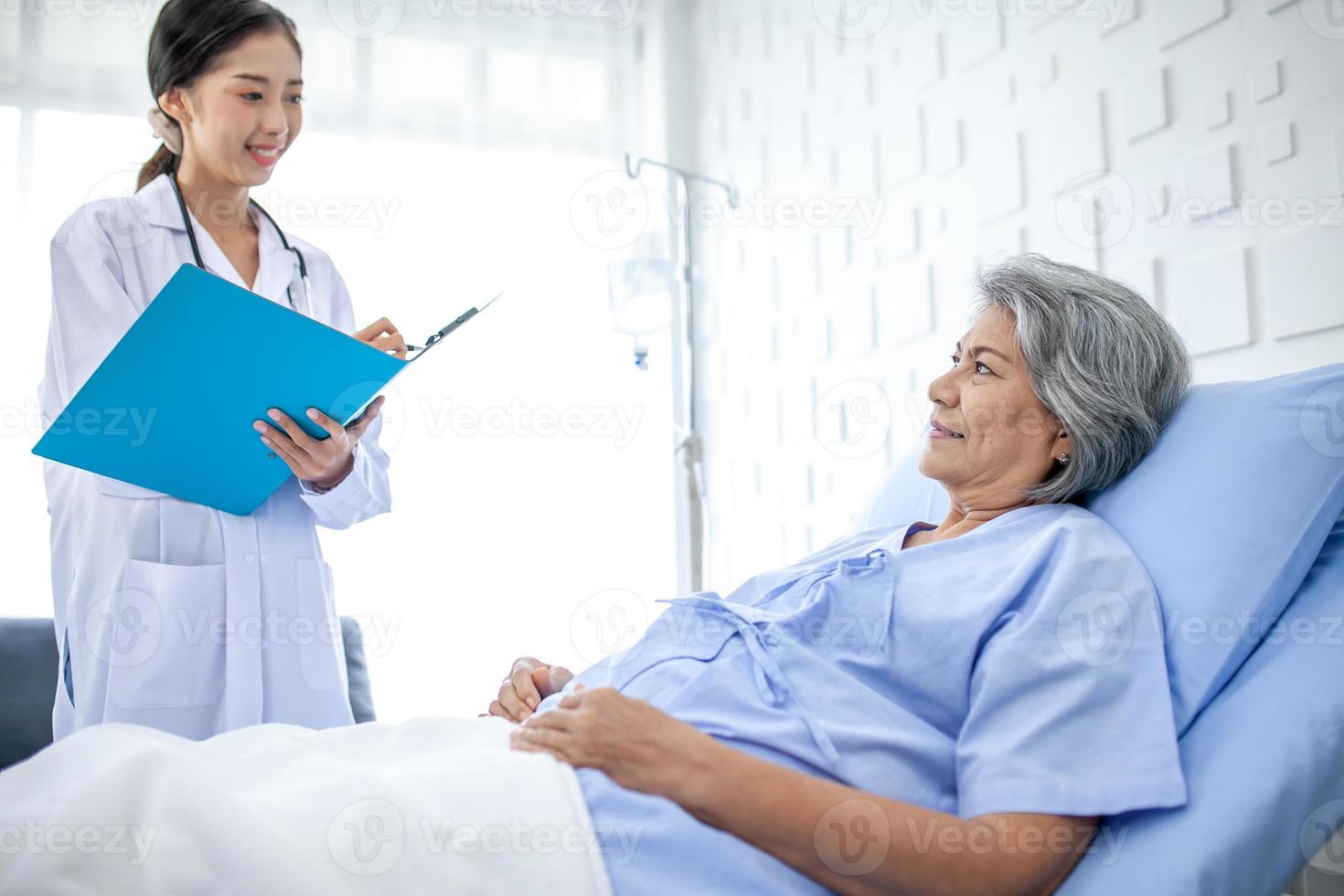 Beautiful asian doctor with stethoscope and document folder, examine the symptom for patient in the recovery room. Healthcare and medicine concept. photo