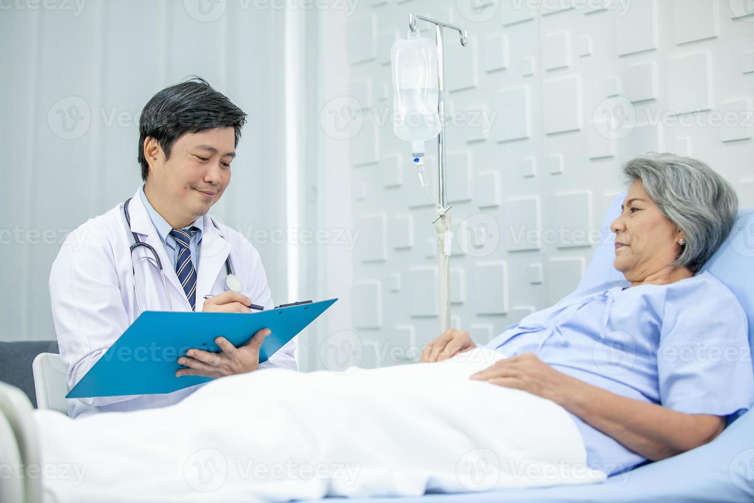 asian doctor with stethoscope and document folder, examine the symptom for patient in the recovery room. Healthcare and medicine concept. photo