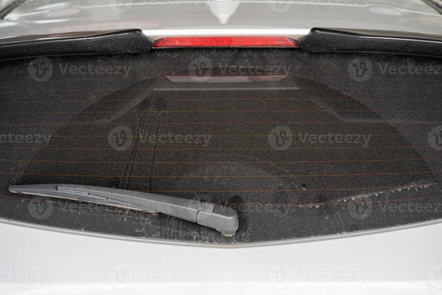 rear window hatchback dirty car rear view on a dusty glass. Dirty and dusty rear window of a white or gray car. Do not forget to wash your cars manually or at car washes photo