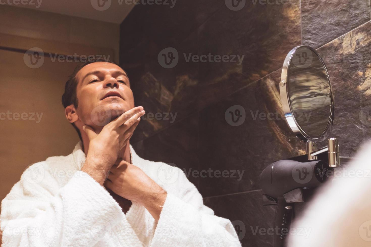 Mid adult man applying moisturizer after shaving. photo