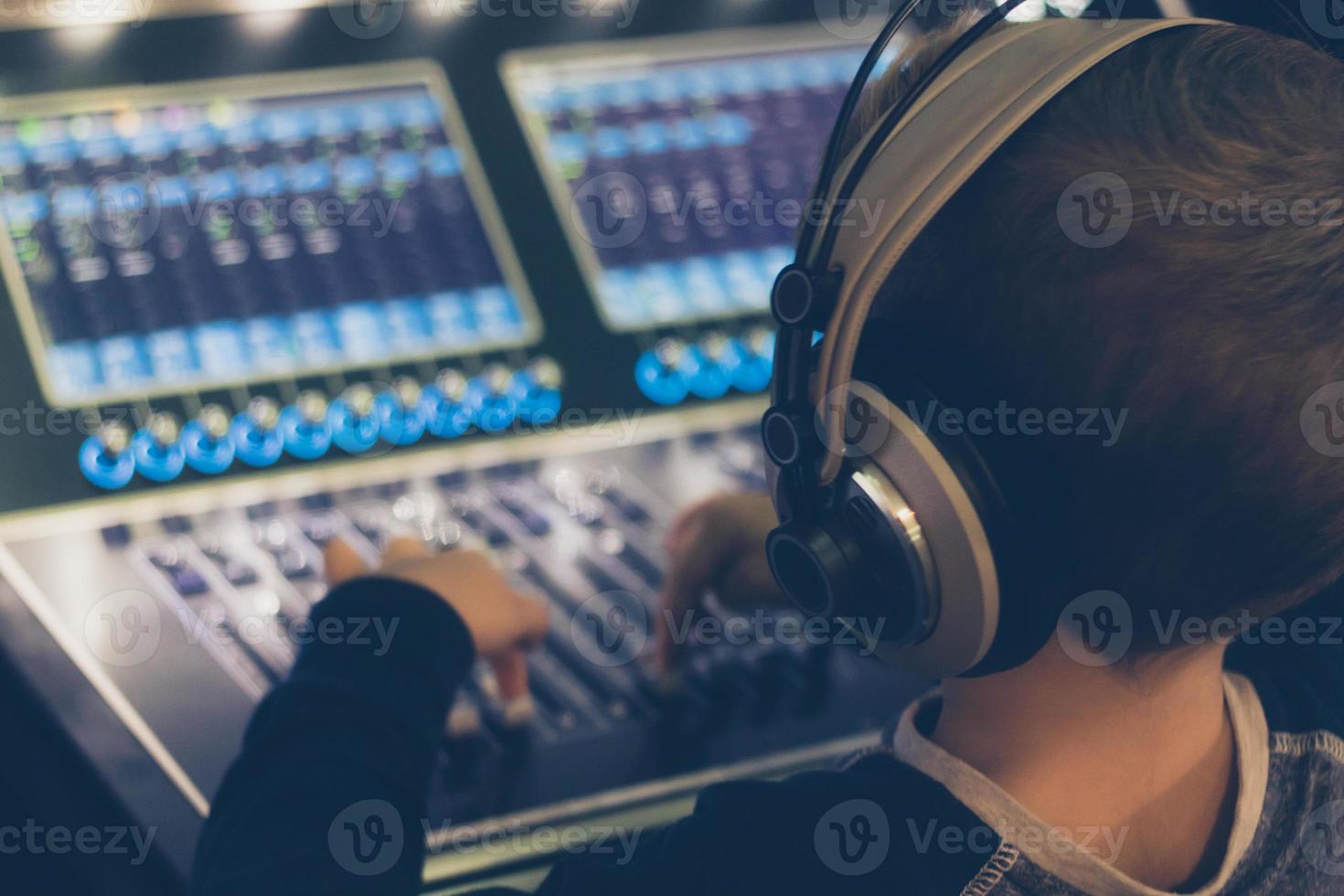 Small boy with headphones editing music in recording studio. photo