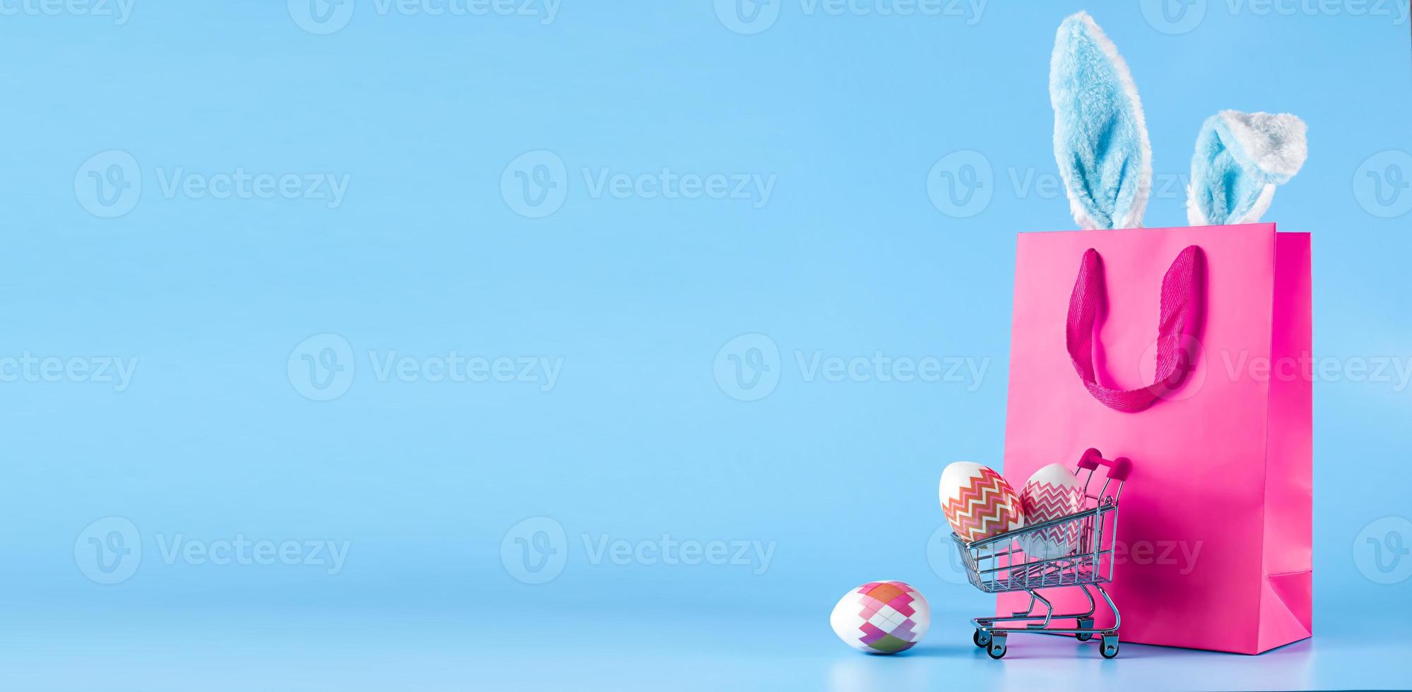 Easter banner, gift bag and shopping cart on a blue background. The concept of Easter sale, shopping, delivery of goods for the holiday photo