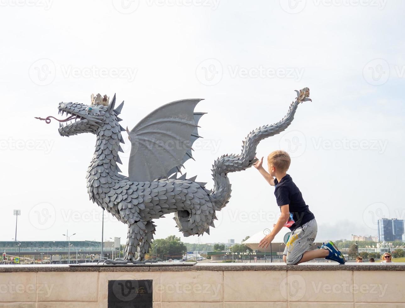 el niño toca la estatua del dragón. el símbolo de la ciudad. foto