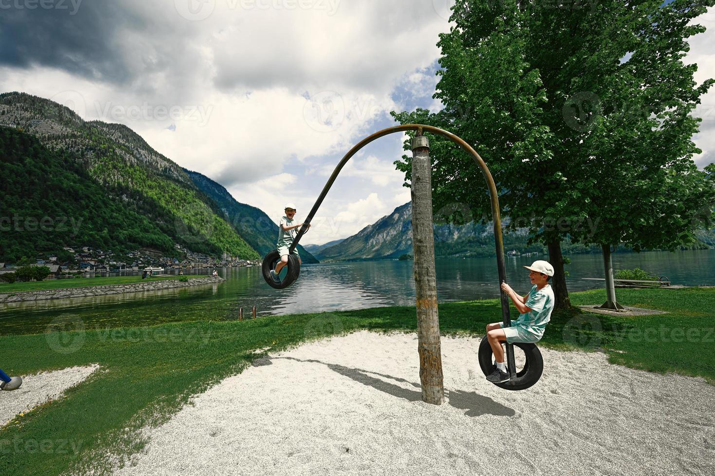 Two brothers ride on a swing from car tires at Hallstatt, Austria. photo