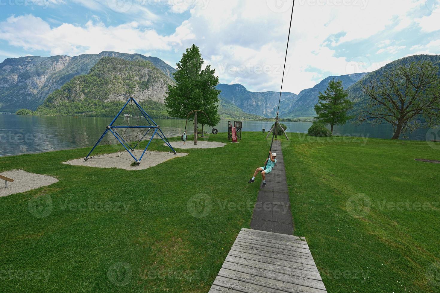 niño columpiándose en la cuerda en el patio de recreo hallstatt, austria. foto